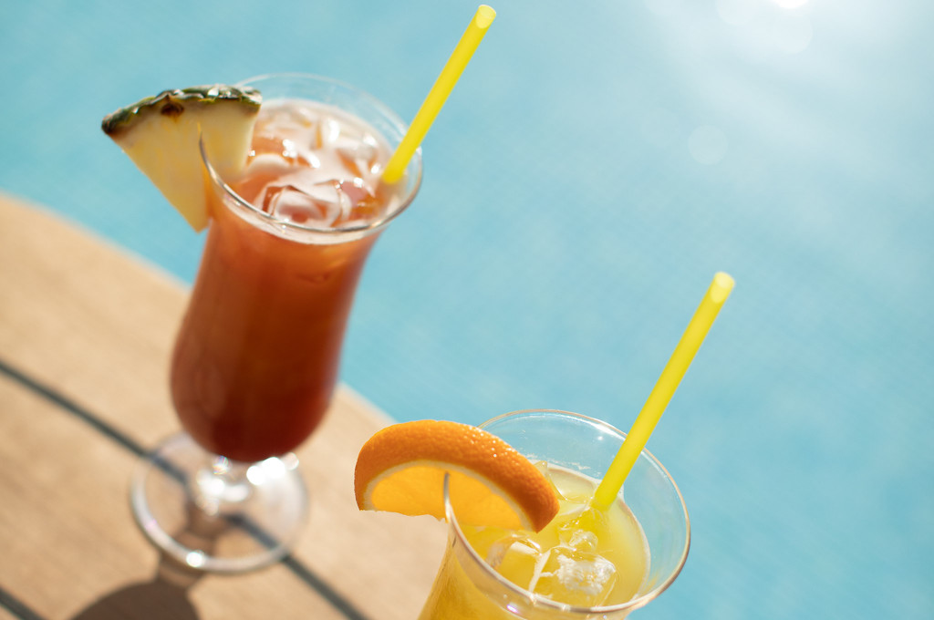 Bunte Cocktails mit Früchten am Pooldeck bei Sonnenschein über dem Meer genießen.