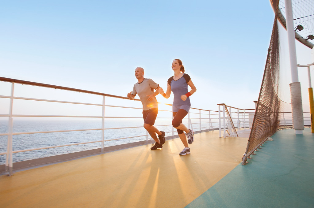 Zwei Läufer joggen auf dem Schiffsdeck mit Meerblick und Geländer zum Joggen.