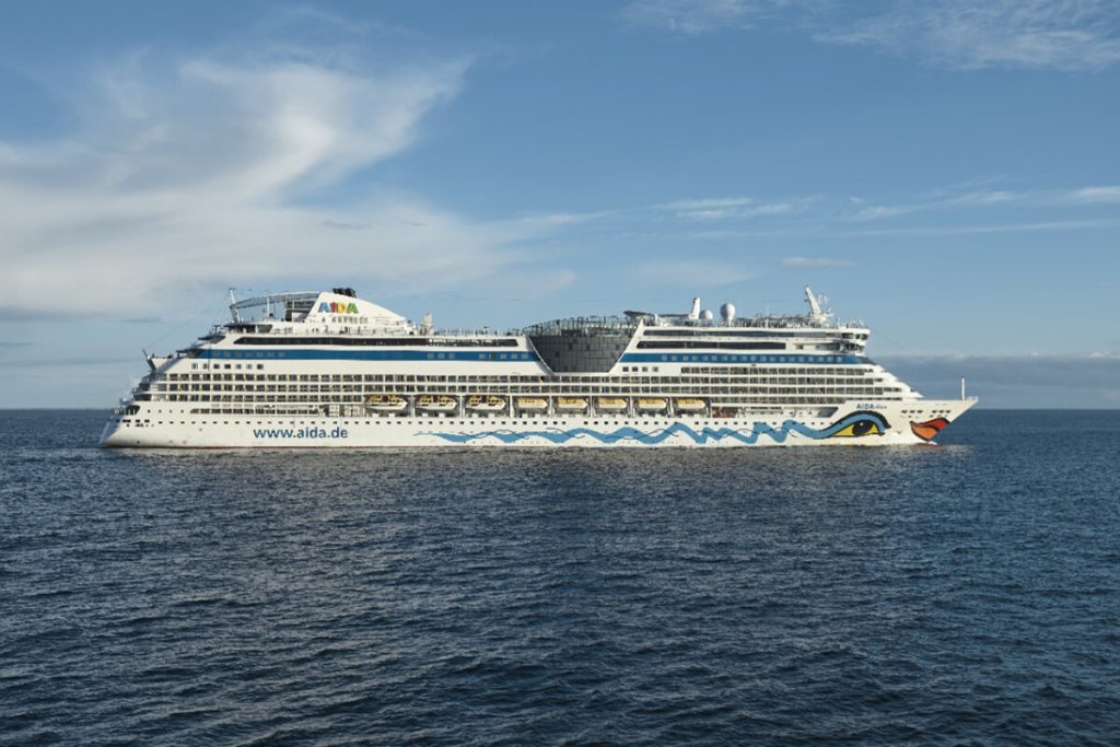 Kreuzfahrtschiff in Seitenansicht auf offener See, am Bug der charakteristische Kussmund.