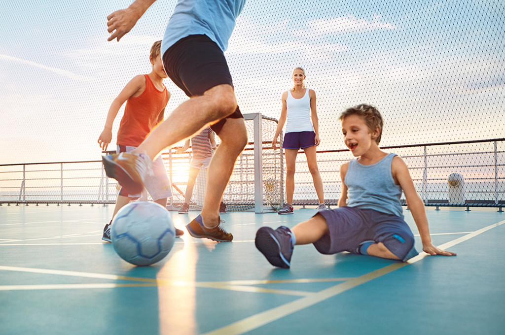 Gruppe mit Kindern spielt Fußball auf dem Sportdeck eines Kreuzfahrtschiffes