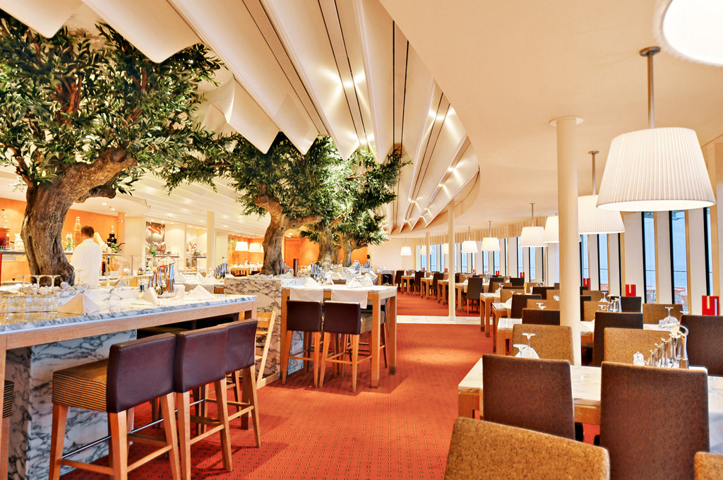Elegantes Bella Vista-Restaurant mit modernen Möbeln, grünen Elementen und Meerpanorama.