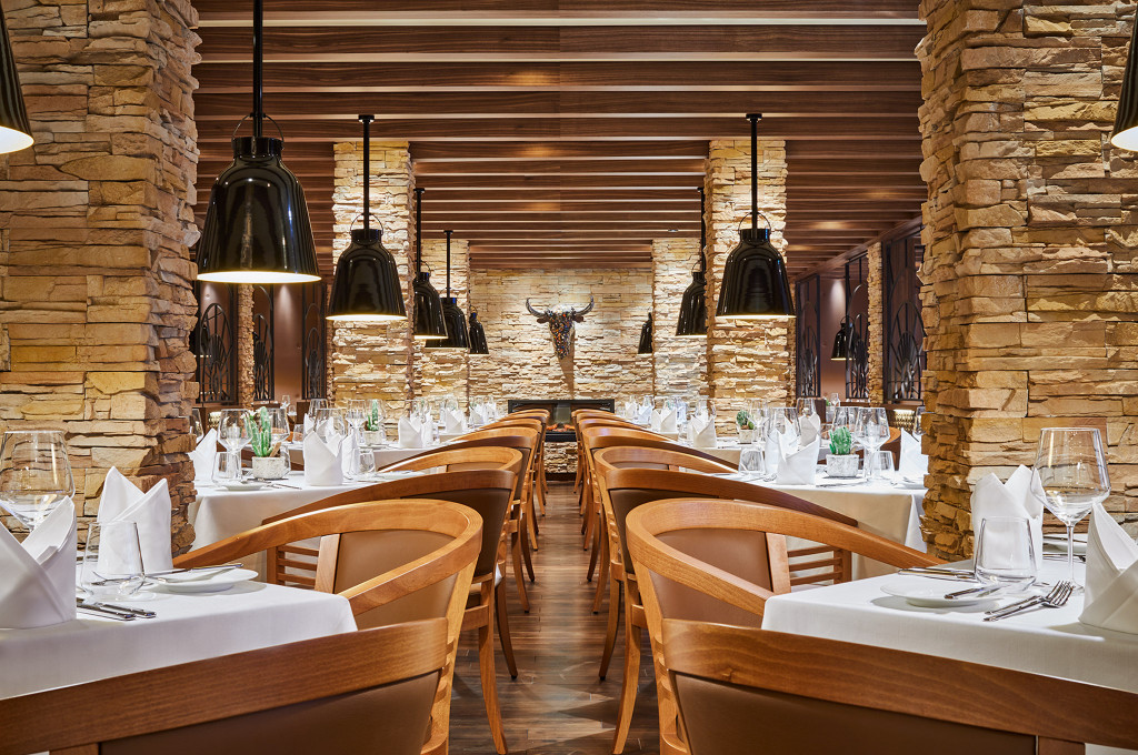 Churrascaria Steakhouse mit Steinwänden, eleganten schwarzen Leuchten und gehobenes Setting.