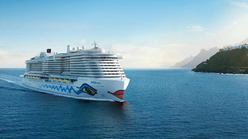 AIDAnova Kreuzfahrtschiff mit charakteristischen Farben vor Küstenlandschaft und Bergkulisse.