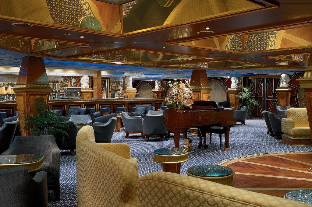 Elegante Lounge auf der Carnival Conquest mit Sesseln und Bücherschränken