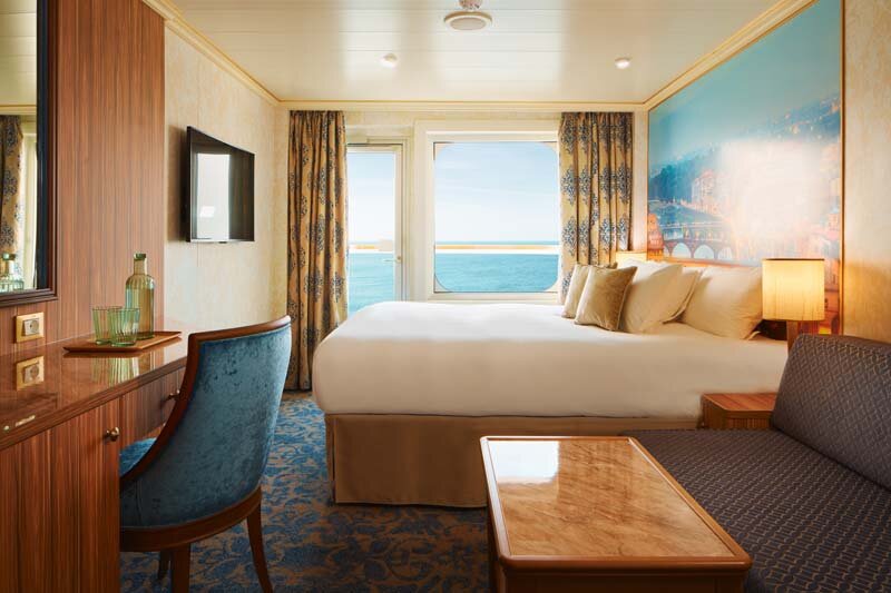 Balkonkabine auf der Carnival Firenze mit modernem Design, Doppelbett und Balkon zum Meer.