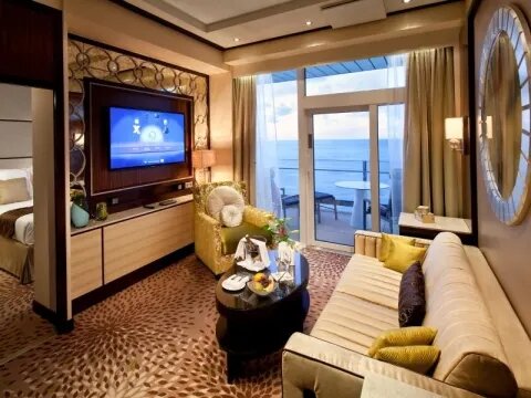 Celebrity Suite auf der Celebrity Reflection mit elegantem Wohnbereich, Flachbildschirm und Balkon mit Meerblick.