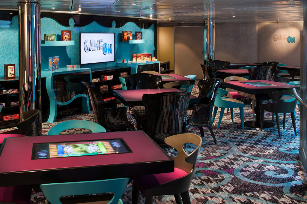 Farbenfroher Game On Kinder-Spielbereich mit türkisen Wänden, bunten Stühlen und Displayscreens.