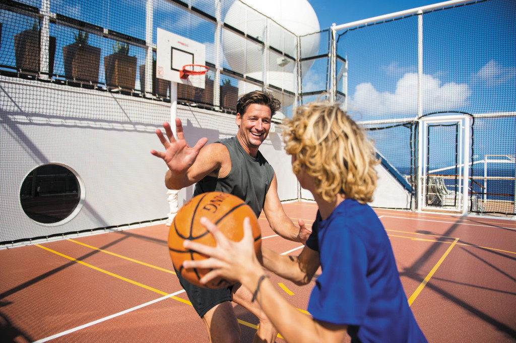 Gäste spielen Basketball auf dem Außendeck der Celebrity Reflection mit Netzumgrenzung.