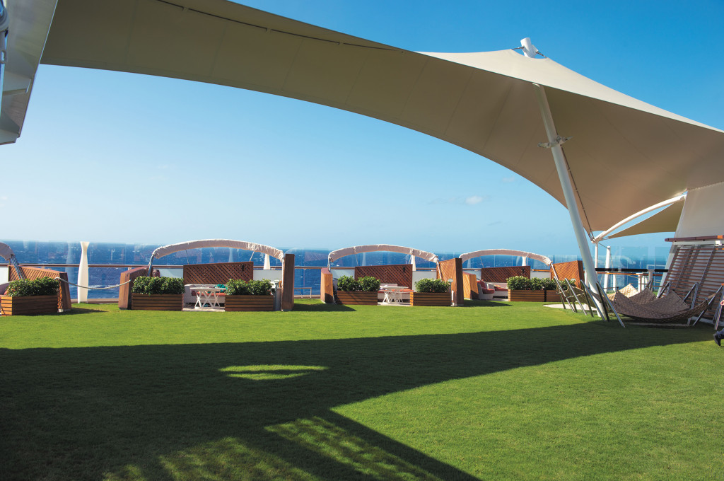 Rasenartiges Außendeck von The Lawn Club mit Meerblick, Sonnenschutz und Sitzbereichen.