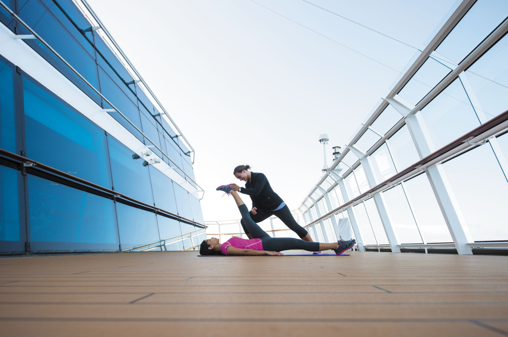 Yogakurs auf dem Außendeck mit Trainerin unter freiem Himmel auf der Celebrity Reflection.