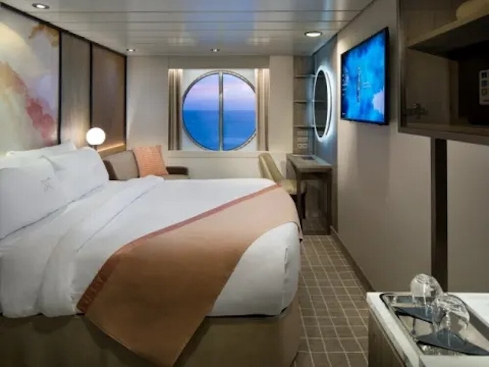 Außenkabine mit Doppelbett, Sitzecke und Bullauge auf einem Hochseekreuzfahrtschiff