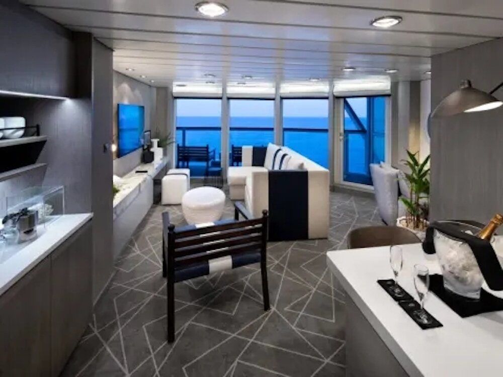 Celebrity Suite auf der Celebrity Summit mit modernem Wohnbereich, Balkon und Champagnerkühler mit Meerblick.