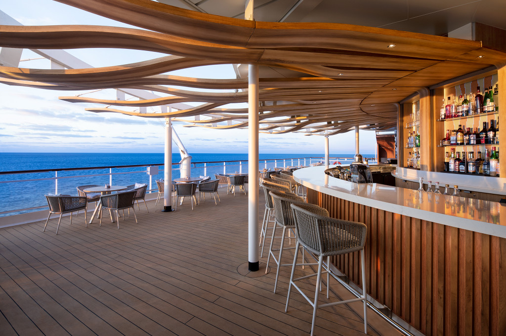 Moderner Bar-Bereich auf dem Sonnendeck mit Ozeanblick, Stühlen und Bartresen zur Getränkeeversorgung.