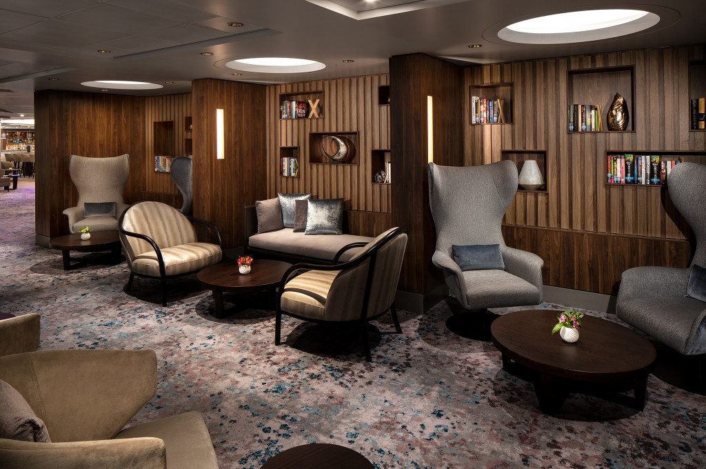 Elegante Lounge mit dunkler Holzvertäfelung, komfortablen Sesseln und Bücherregalen im Rendezvous Lounge.