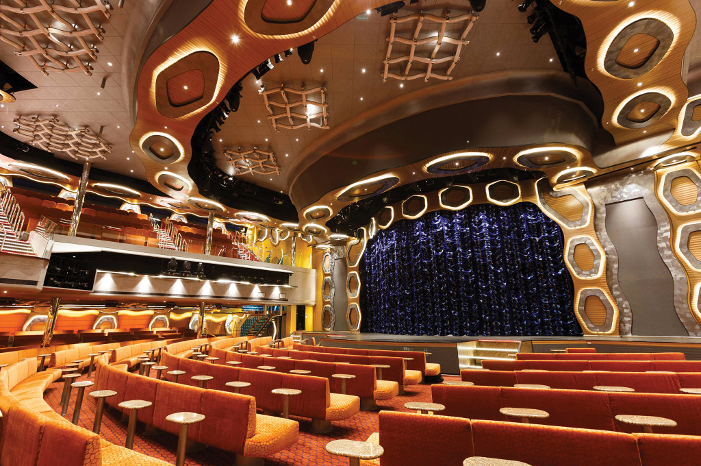 Großes Theater mit Bühnenlicht und Sitzreihen für Shows auf einem Hochseeschiff.