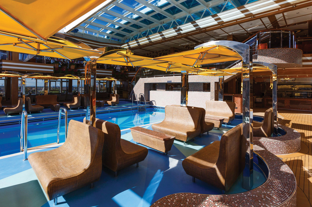 Lido-Pool mit Liegestühlen und Sonnenschirmen auf dem Sonnendeck eines Hochseeschiffs.