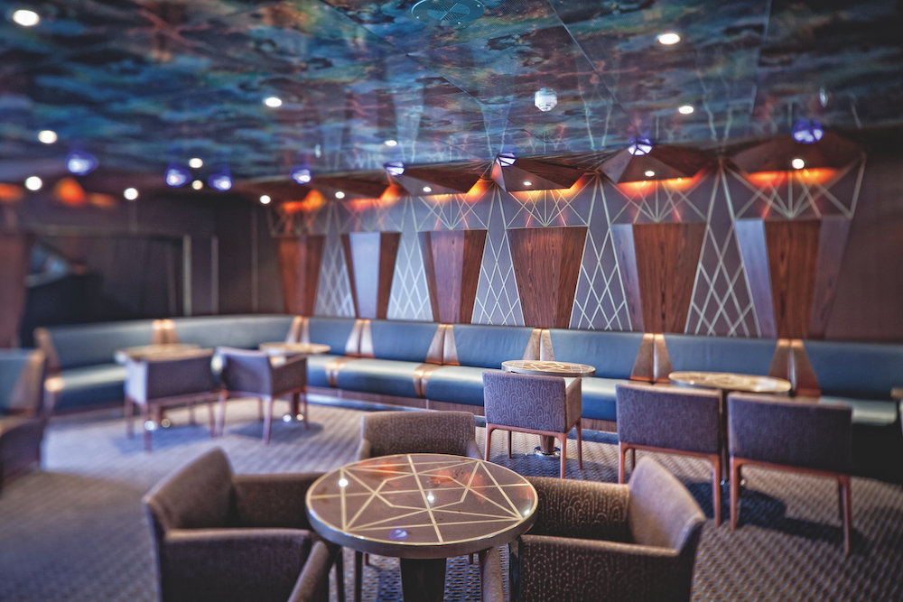 Stimmungsvolle Lounge Chéri auf der Costa Fascinosa mit bunter Designdecke und modernem Sitzmobiliar.