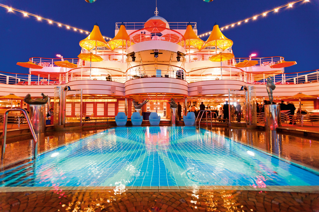 Costa Fascinosa Poolbereich mit blauem Wasser, Liegestühlen und Schiffsdeck im Hintergrund.