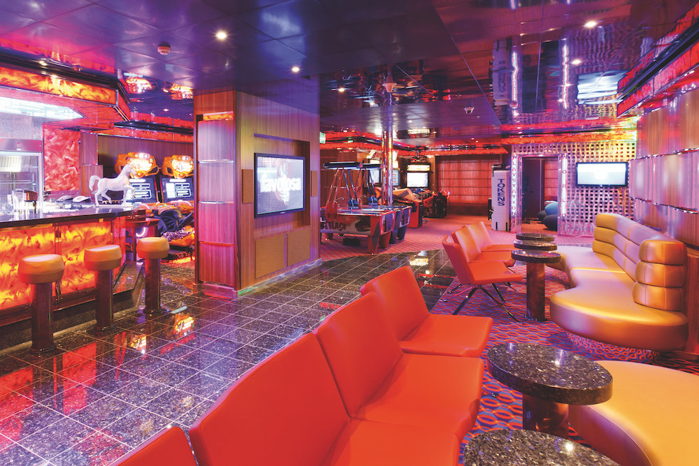 Club Cavallo Bianco Jugendbereich auf der Costa Favolosa mit Spielautomaten, bunter Beleuchtung und Lounge-Sitzen.