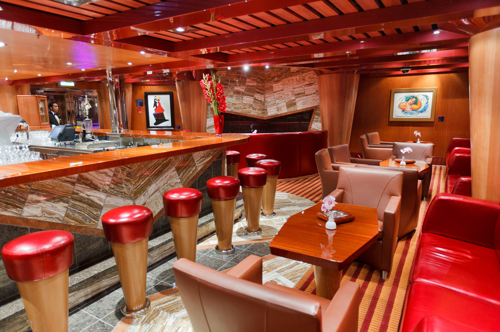 Costa Favolosa Bar Classico Montespan mit Holzpaneelen, roten Barhockern und eleganter Ausstattung.
