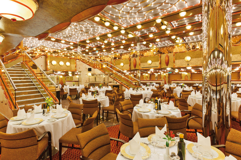 Costa Favolosa Duca d'Orleans Restaurant mit zweigeschossiger Architektur, gedeckten Tischen und eleganter Beleuchtung.