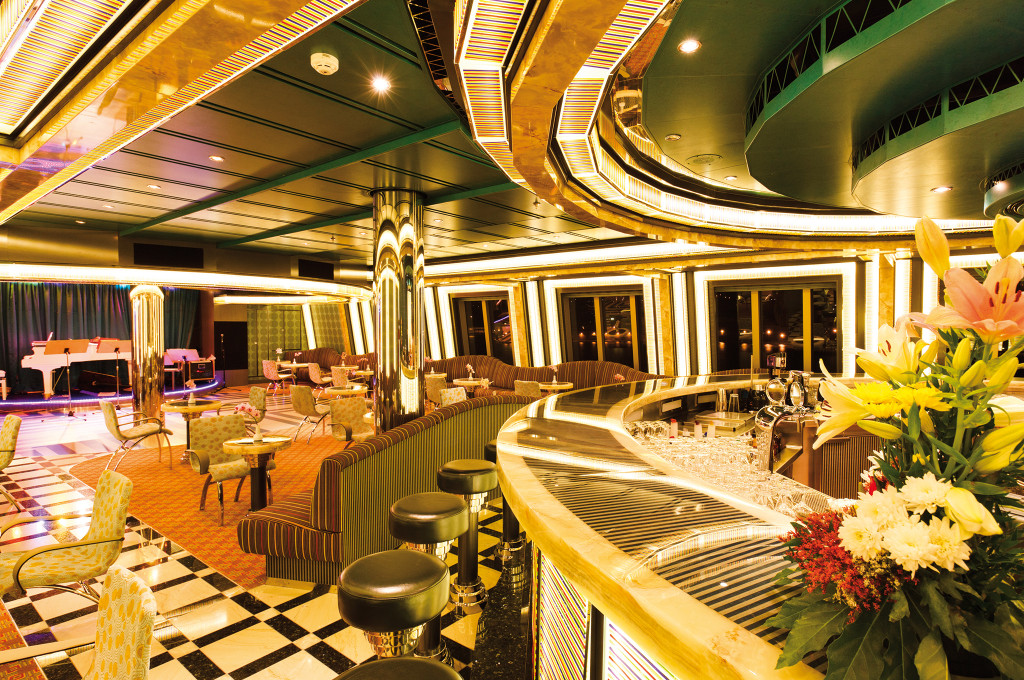 Costa Favolosa Ballsaal Pompadour mit goldenem Design, grünen Akzenten und Panoramafenstern.