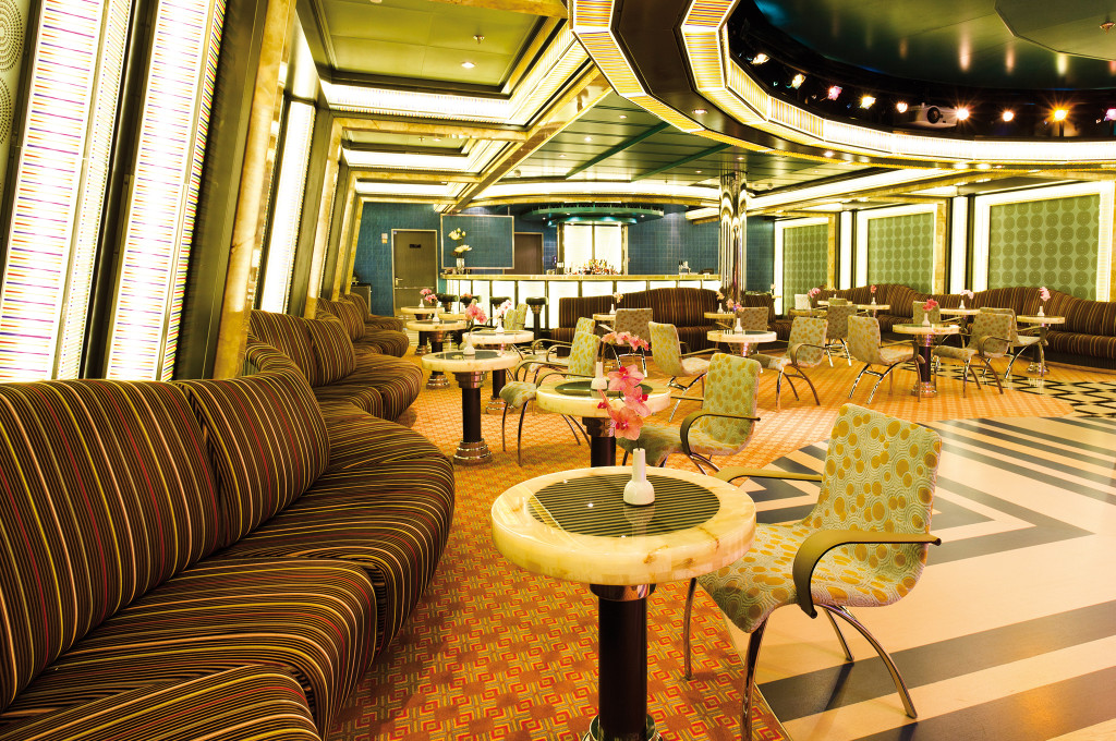 Costa Favolosa Ballsaal Pompadour mit grünen Stühlen, eleganten Tischen und großen Fenstern.