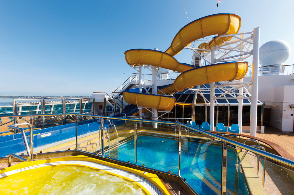 Costa Favolosa Wasserrutsche mit zwei gelben Röhren, Poolbereich und Meeransicht.
