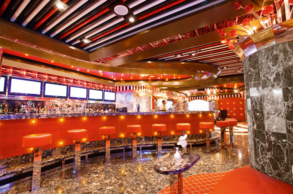 Bar mit roten Barhockern, beleuchteter Theke und moderner Innenausstattung auf der Costa Pacifica.