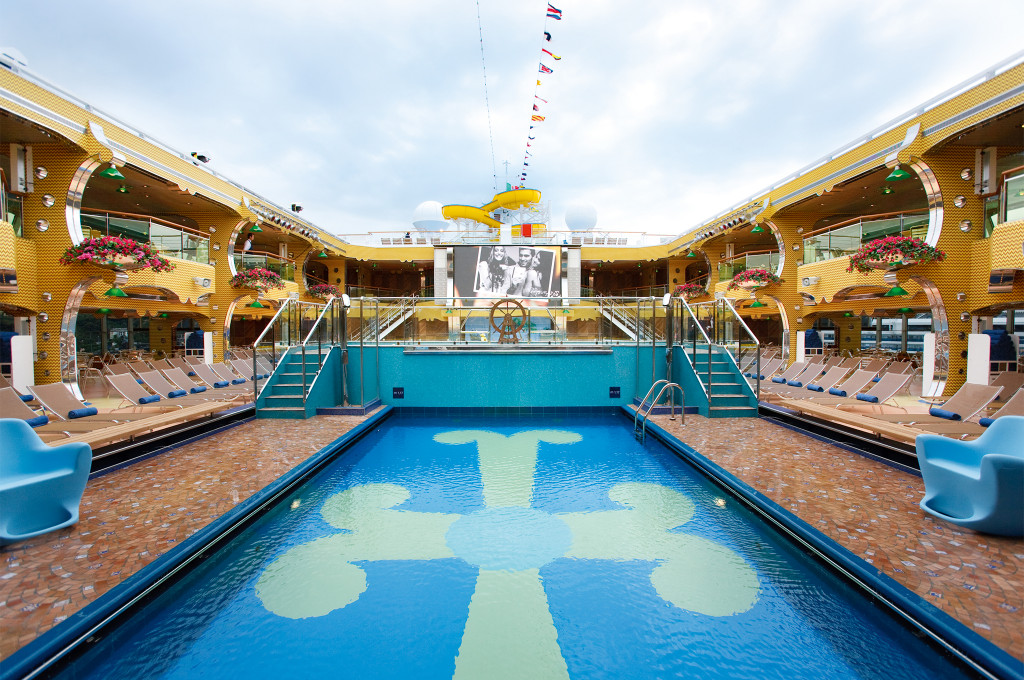 Pooldeck mit großem Swimmingpool, Liegestühlen und gelbem Sonnenschutz an Bord der Costa Pacifica.
