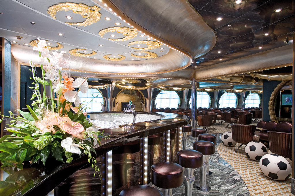 Bar mit elegantem Design, Blumendekoration, roten Barhockern und großen Panoramafenstern mit Meerblick.