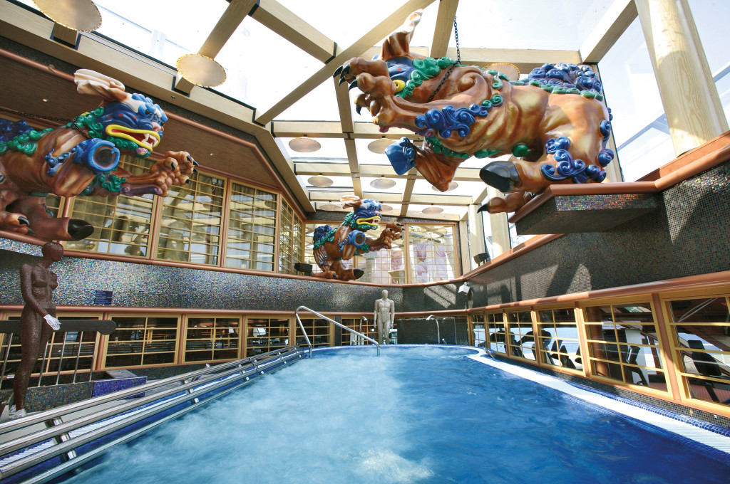 Indoorpool mit Glasdach, dekorativen Wasserspeierern und blauem Wasserbecken auf der Costa Serena.