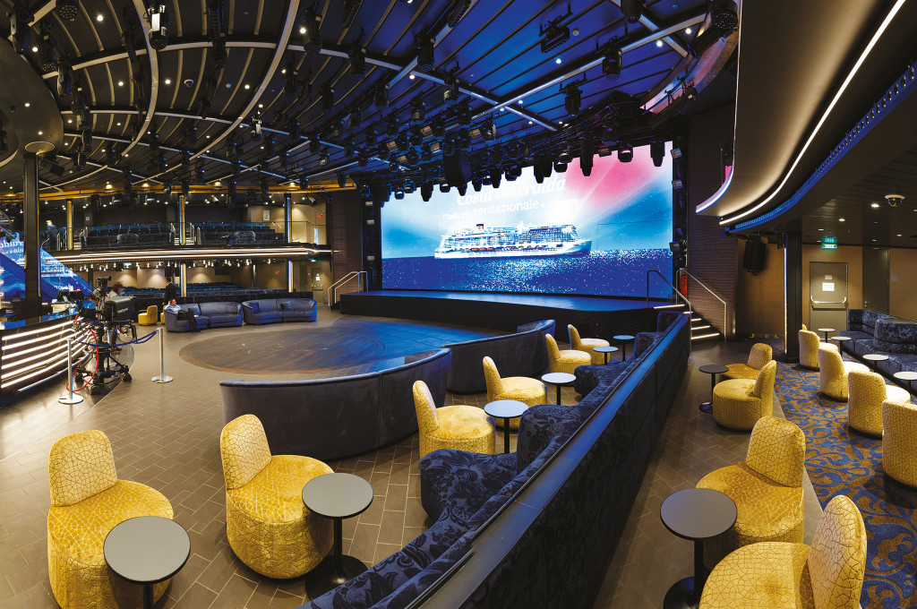 Theater auf der Costa Smeralda mit großer LED-Bühne, goldenen Loungesesseln und modernem Showbereich.