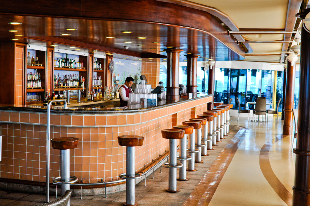 Moderne Bar mit Holz-Theke und langen Barhockern mit Fensterblick auf der Grand Princess.