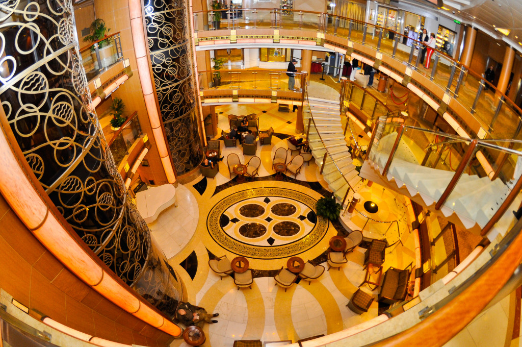Grandioses Atrium mit runden Säulen, geometrischen Ornamenten und mehreren Decksebenen auf der Grand Princess.
