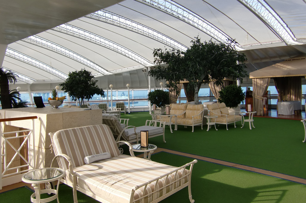 The Sanctuary Privatbereich mit Liegestühlen auf Grünfläche und großen Fenstern auf der Grand Princess.
