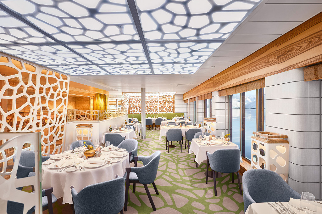 Elegantes Hauptrestaurant mit organischem Deckenpaneel, weißen Tischdecken, Gittertrennwänden und Blick auf Fjordlandschaft