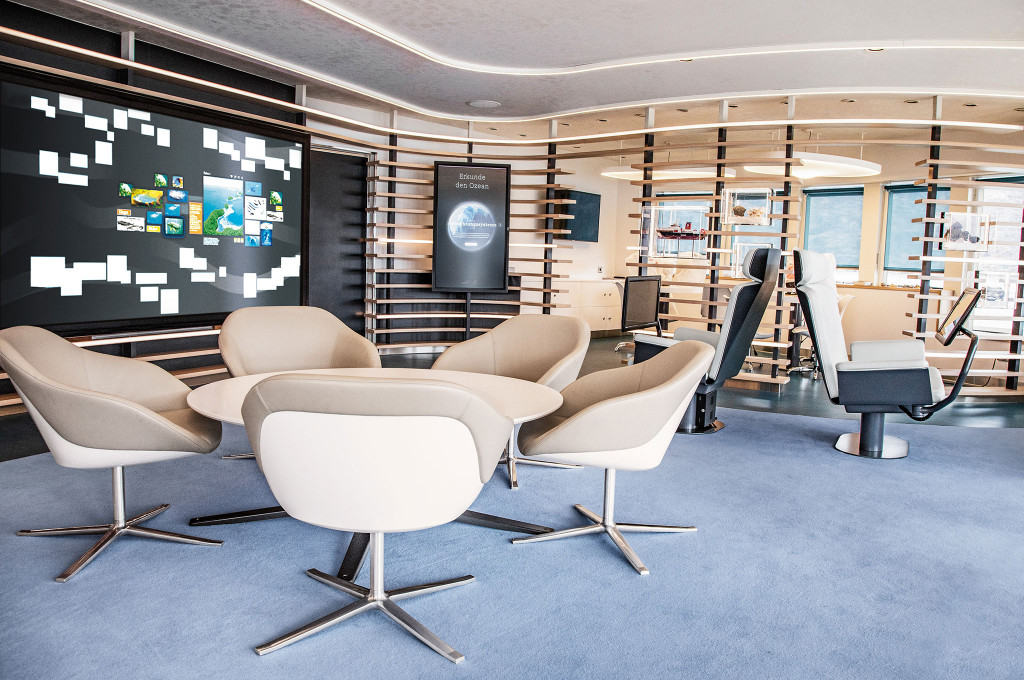 Ocean Academy mit großem interaktivem Touchscreen, Drehsesseln, Holzlamellen-Wänden und Computerarbeitsplätzen