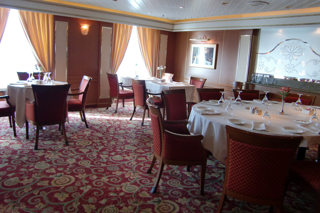 Elegantes Restaurant mit formal gedeckten Rondellen-Tischen und Weinrot-Dekoration auf der Island Princess.