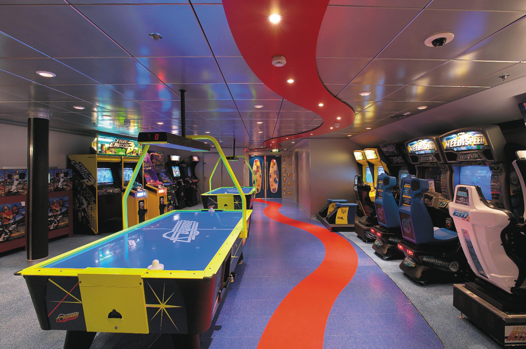 Arcade Spielhalle mit Airhockey-Tisch, Rennsimulatoren und mehreren Arcade-Automaten unter stimmungsvoller Beleuchtung.