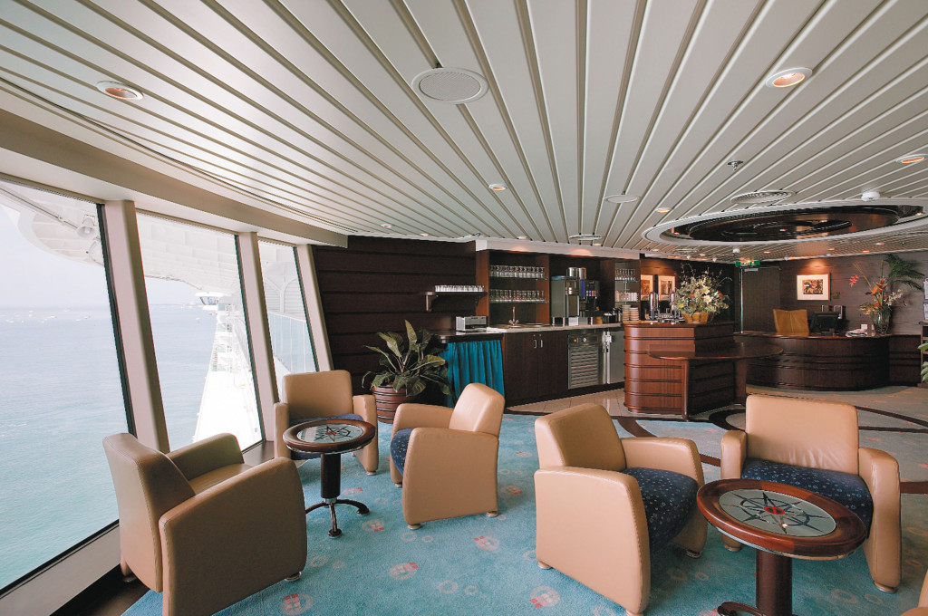 Concierge Lounge mit gepolsterten Sesseln, Beistelltischen und kleiner Bar mit Panoramafenstern zum Meer.