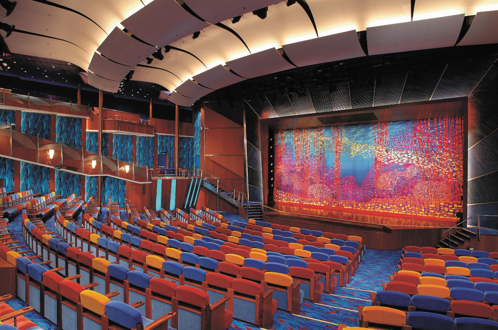 Theater des Schiffes mit farbenfrohen Sitzreihen, beleuchteter Bühne und kunstvoll gestaltetem Bühnenvorhang.