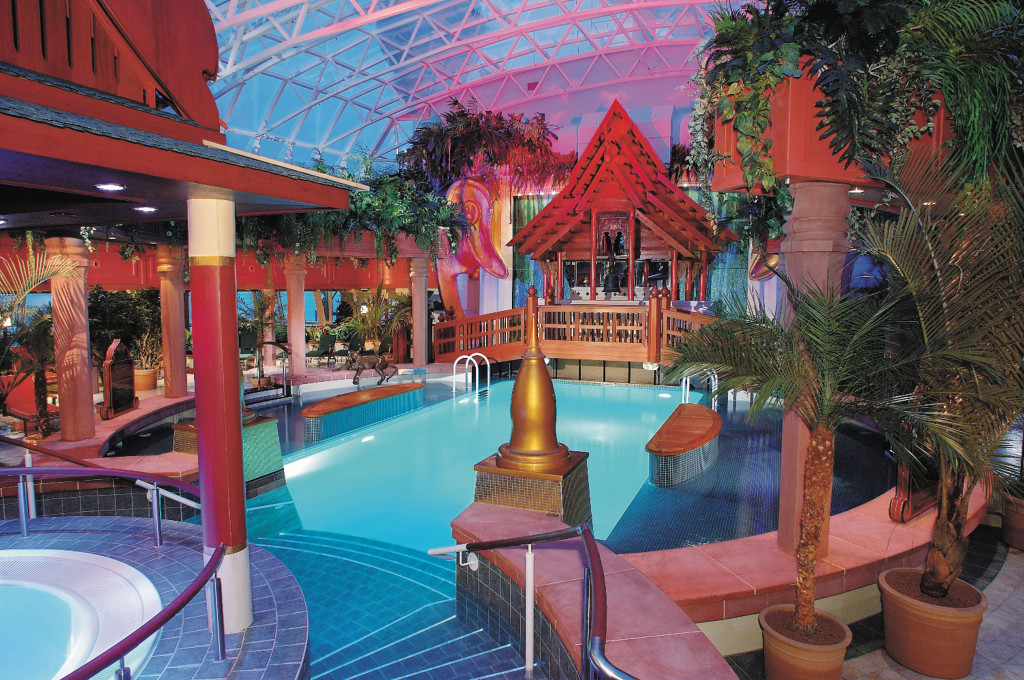 Solarium mit verglastem Innenpool, Whirlpool und asiatisch inspirierter Dekoration unter einer Glaskuppel.