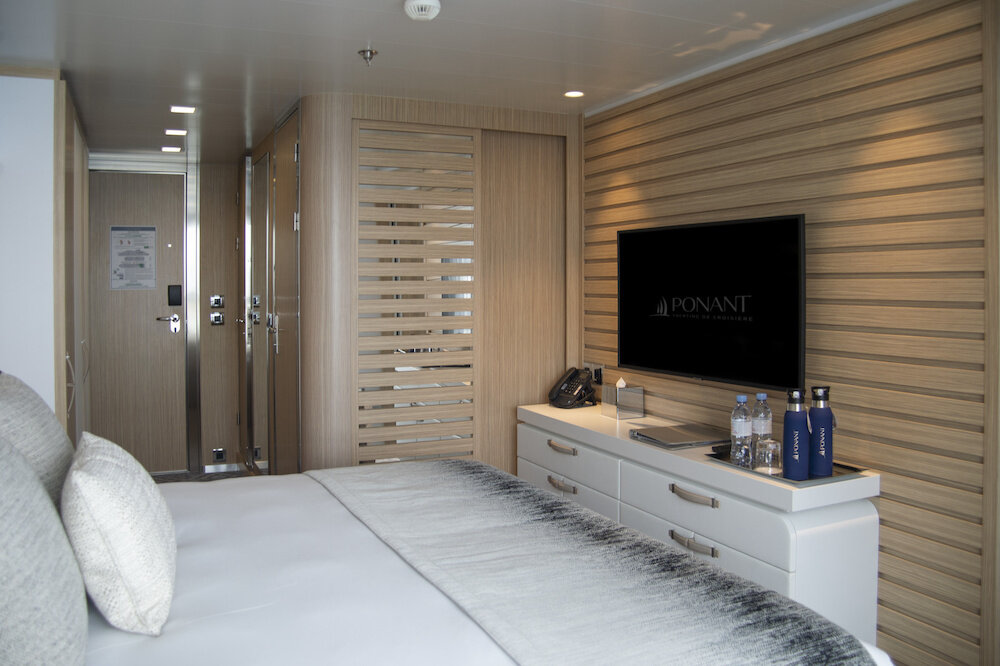 Suiten-Einrichtung mit Holzverkleidung, Fernseher und Kleiderschrank auf einem Hochseekreuzfahrtschiff