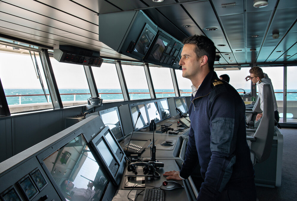 Schiffsbrücke der Le Bellot mit Offizier an Navigationspult und Blick auf das raue Meer