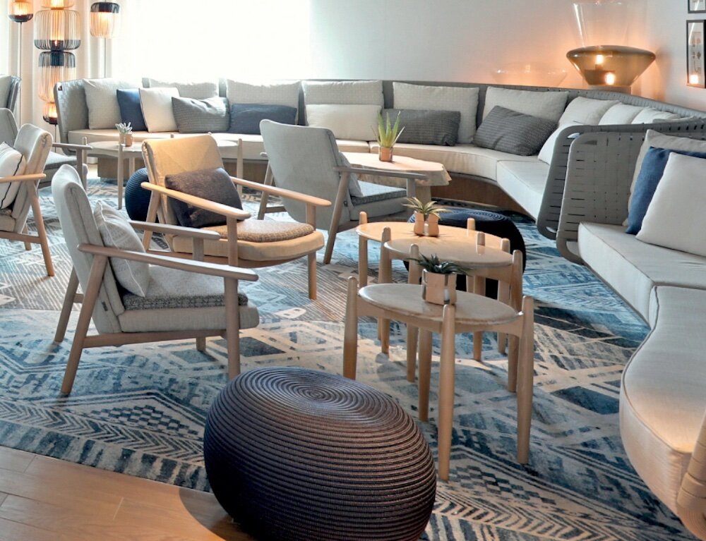 Moderne Lounge der Le Bellot mit geschwungenem Sofa, Holzsesseln und stimmungsvoller Beleuchtung