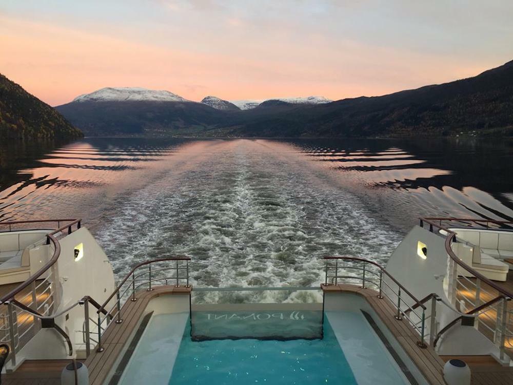 Beleuchteter Heckpool der Le Bellot mit PONANT-Schriftzug bei Dämmerung im norwegischen Fjord