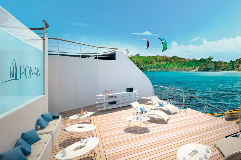 Sonnendeck mit Liegestühlen und Loungebereich bei tropischer Küste und Kitesurfern.