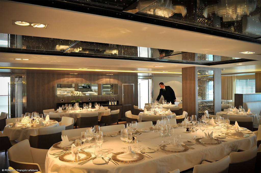Elegantes Bordrestaurant mit festlich gedeckten Tischen, Kristalldecken und Kellner bei der Tischvorbereitung.