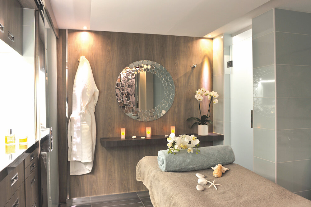 Spa-Behandlungsraum der Le Boréal mit Massageliege, Orchideen und dekorativem Rundspiegel